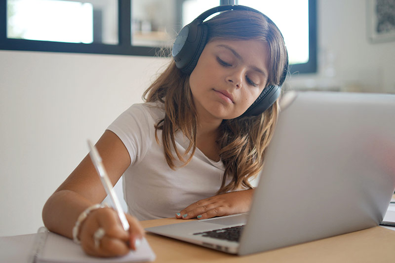 Student with headphones working at a laptop