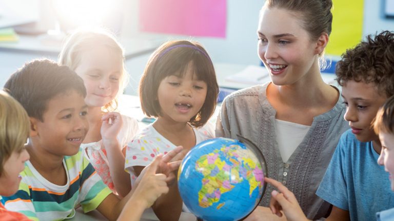 Teacher and students studying globe