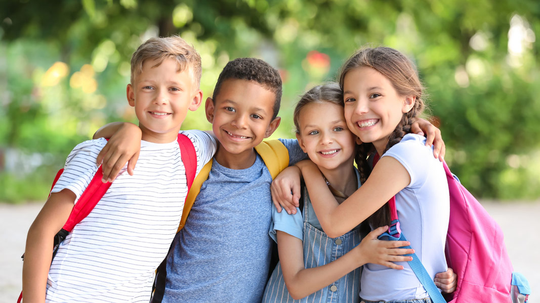 4 happy school children standing together