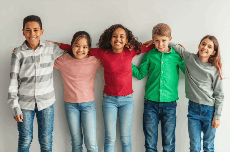 Five smiling students pose in front of a wall together